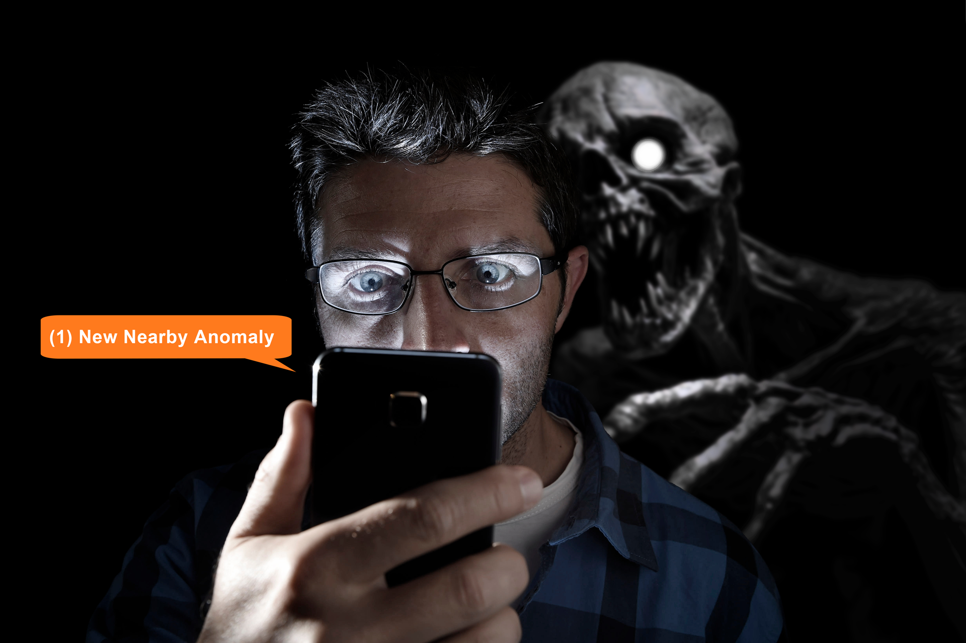 A man in the dark looks at his phone while a monster lurking behind him is revealed by the screen's glow